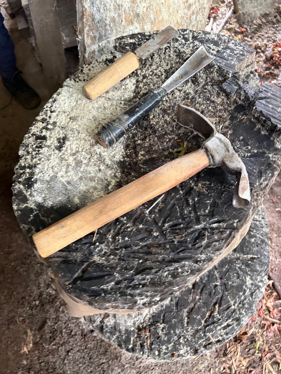 Herramientas artesanales de Edgardo: formones y martillo sobre tronco